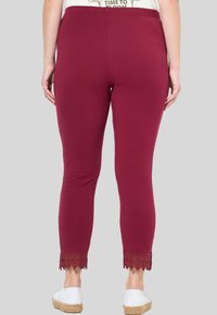 Leggings burdeos con una cintura elástica, terminando en un ribete de encaje en los puños. Diseño ajustado y suave con una textura blanda.