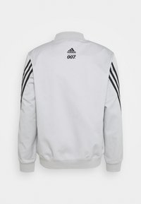 Light gray bomber jacket with black Adidas stripes on sleeves and "007" logo on the back. Ribbed collar and cuffs. Smooth texture.