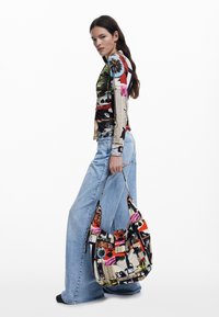 Sac hobo imprimé coloré avec un mélange de motifs, y compris des éléments floraux et graphiques, doté d'une seule sangle pour le porter.
