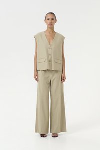 Gilet beige senza maniche con scollo a V profondo, chiusura con bottoni e due tasche frontali, abbinato a pantaloni a gamba larga coordinati.