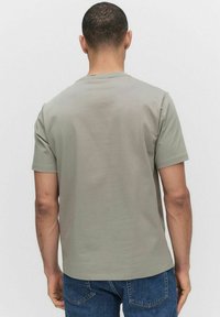 Grijze t-shirt met korte mouwen en een ronde hals, gemaakt van zachte stof. Eenvoudig ontwerp, zonder patronen, gedragen met blauwe spijkerbroek.