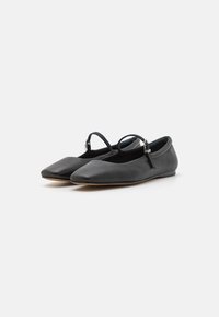 Bailarinas de cuero negro con puntera afilada, que cuentan con una delgada correa en el empeine y un diseño minimalista. Textura suave y suela flexible.