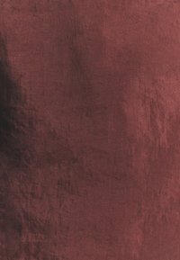 Tessuto borgogna testurizzato con una leggera lucentezza, caratterizzato da una superficie leggermente stropicciata e una finitura liscia e morbida.