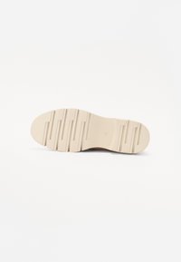 Suola di scarpa in gomma beige con un motivo ondulato e caratteristiche di grip testurizzato. Punta arrotondata e design segmentato per flessibilità e supporto.