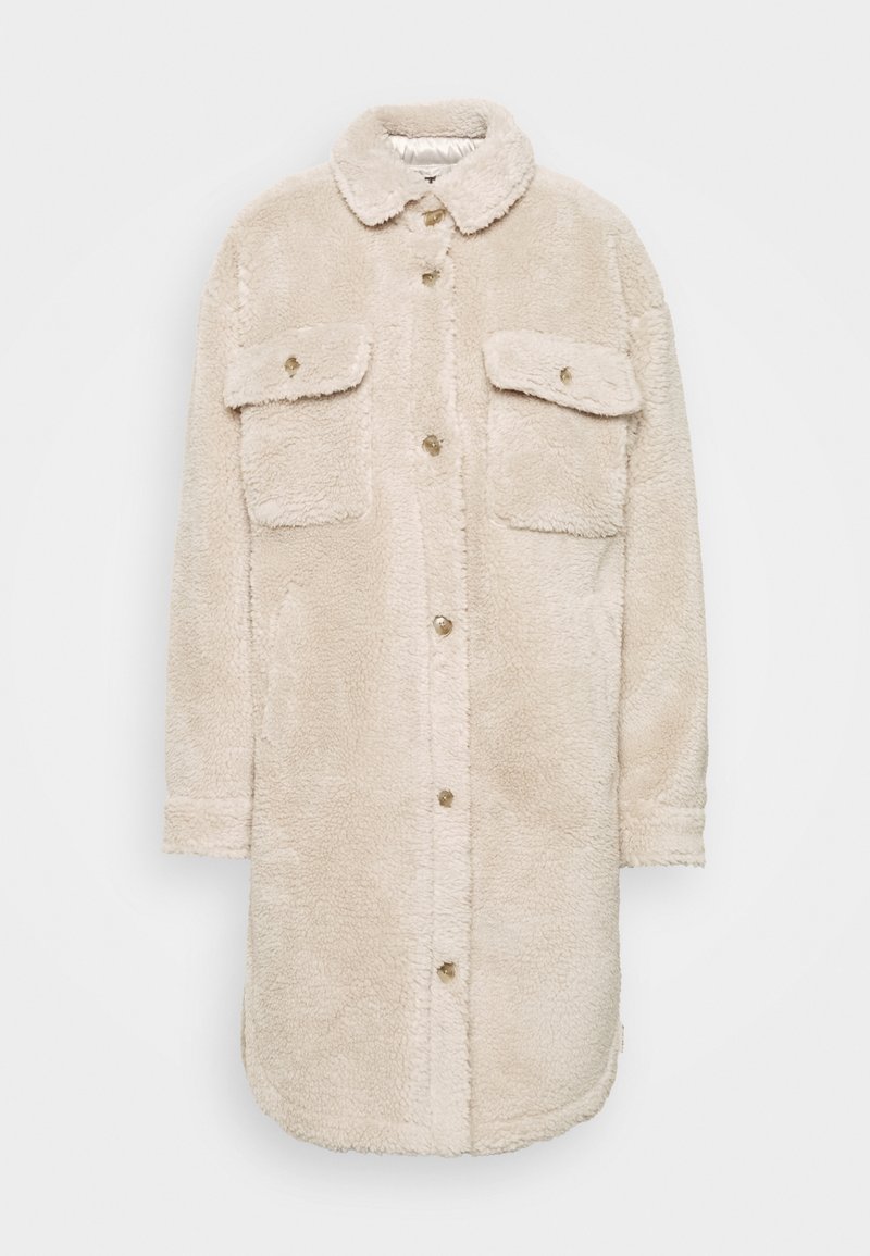 Béžový kabát z umělé kožešiny s límcem, dvěma náprsními kapsami a zapínáním na knoflíky vpředu. Má jemnou texturu a zaoblený spodní lem.