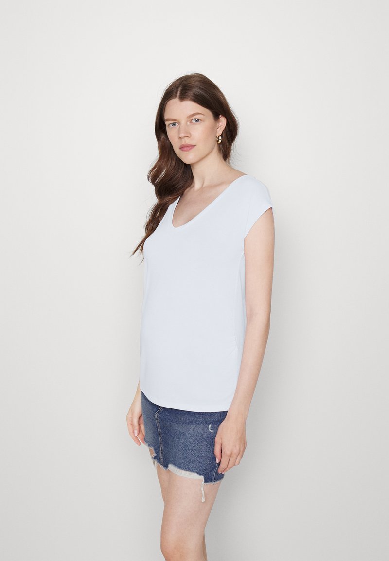 Top azul claro de mangas curtas com decote em V profundo e bainha curva, combinado com uma saia mini de ganga com bordas desfiadas. Textura suave.