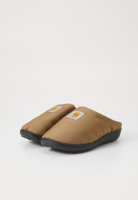 Bruine stoffen instappantoffels met een gequiltde textuur en zwarte rubberen zolen. Voorzien van een wit en oranje logo-opdruk aan elke kant.
