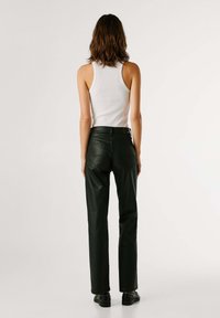Pantaloni in pelle nera con vestibilità dritta, cuciture dettagliate e due tasche posteriori. Indossati con un top bianco, visti da dietro.