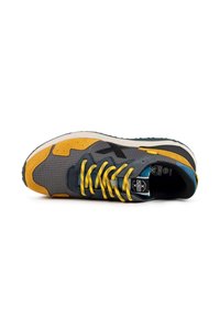 Zapatilla con parte superior de tela gris, acentos de gamuza amarilla y cordones amarillos. Presenta un diseño estampado, suela acolchada y suela exterior de goma negra.
