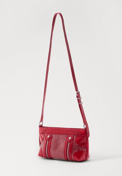 Sac d'épaule en cuir rouge avec un corps texturé, des accents cloutés et une longue bandoulière réglable. Comprend des poches zippées à l'avant.