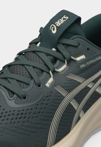 Σκούρο πράσινο παπούτσι τρεξίματος ASICS GEL-CUMULUS 28 με λευκές λωρίδες λογότυπου και λεπτομερείς κορδόνια σε αναπνεύσιμο πλεκτό επάνω μέρος.