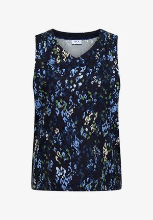 Femme aux longs cheveux bruns et taches de rousseur portant une robe bleu marine sans manches avec un motif floral abstrait vert, blanc et bleu clair.