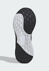 Black and white sneaker sole featuring textured rubber for grip, geometric tread patterns, and a central oval section for flexibility.