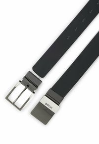 Cintura in pelle nera con una fibbia rettangolare in argento con il marchio "HUGO" inciso. Texture liscia con cinque fori di regolazione.