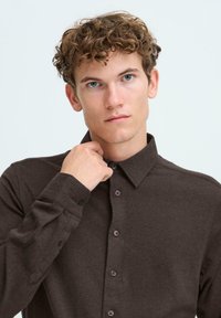 Mørkebrune langermede skjorter med krage, med en subtil tekstur og matchende knapper foran.