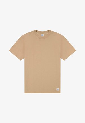 Beige Kurzarm-T-Shirt mit Rundhalsausschnitt und einem kleinen Lee-Logoetikett, das nahe dem unteren Saum auf weißem Hintergrund angenäht ist.