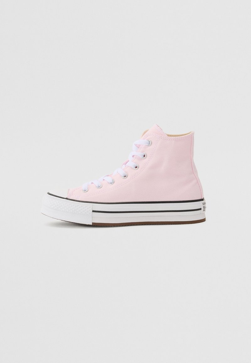 Basket en toile rose montante avec lacets blancs, semelle blanche épaisse avec deux rayures noires, vue de côté sur fond uni.