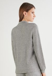 Grauer gerippter Pullover mit langen Ärmeln, Rundhalsausschnitt und strukturierter Oberfläche. Verfügt über einen lockeren Schnitt und ein dezentes Saumdetail.