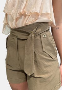 Shorts kaki a vita alta con cintura annodata, tasche strutturate, texture morbida e un piccolo logo accanto alla tasca.
