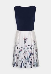 Námořnické šaty bez rukávů s volně splývající sukní s květinovým vzorem v odstínech krémové, fialové a zelené, vyrobené z lehkého materiálu.