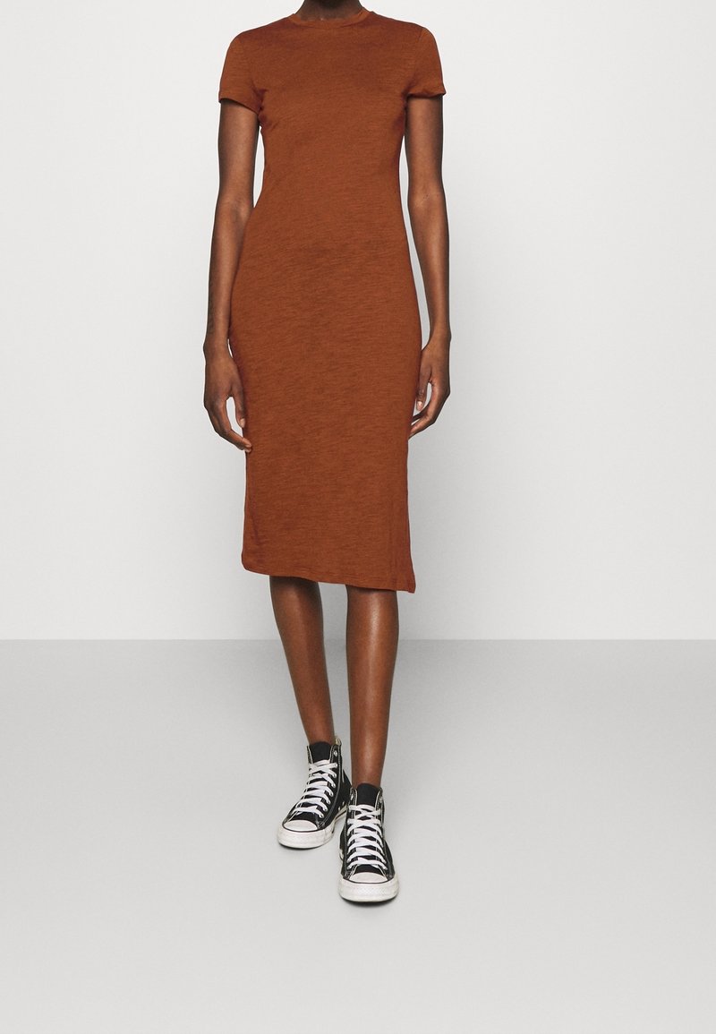 Ruskea, lyhythihainen, vartalonmyötäinen midi-mekko, joka on valmistettu tekstuuri-kankaasta ja yhdistetty mustiin korkeatoppaisiin tennareihin. Yksinkertainen muotoilu, kapea istuvuus.