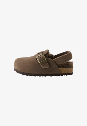 Brauner Wildleder-Clog zum Hineinschlüpfen mit verstellbarem Schnallenriemen, offenem Fersenbereich mit Fellfutter und einer strukturierten Sohle für guten Halt.