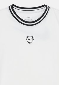 Λευκό μπλουζάκι Nike με στρογγυλή λαιμόκοψη, έχοντας μαύρη και άσπρη ρίγα στον γιακά και μικρό μαύρο λογότυπο Nike μέσα σε ένα ασπίδιο στο στήθος.