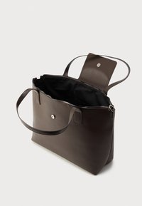 Σκούρο καφέ τσάντα ώμου από δέρμα με δύο λουριά ώμου, ανοιχτό φερμουάρ στην κορυφή και κλείσιμο με μαγνητικό καπάκι, που αποκαλύπτει μαύρη υφασμάτινη επένδυση στο εσωτερικό.