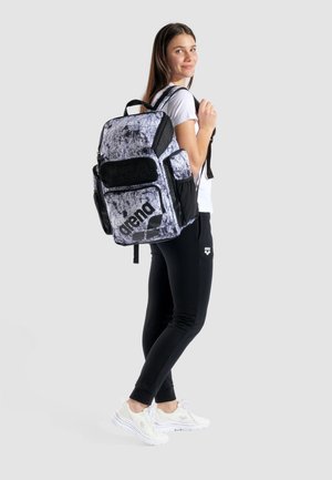 Zaino in bianco e nero con motivo astratto, tasche in rete, più scomparti, spallacci imbottiti e logo stampato sulla parte anteriore.