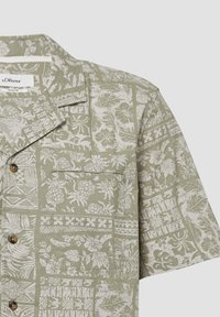 Lichtgroen overhemd met korte mouwen en een patroonontwerp met witte bloem- en geometrische motieven, inclusief een borstzak en knoopdetails.