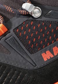 Scarpa sportiva nera con tomaia in mesh e dettagli arancioni, sovrapposizioni in gomma testurizzata e un sistema di lacci bloccabile per una vestibilità sicura.