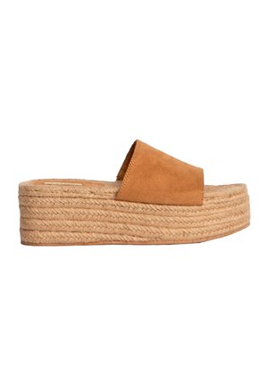 Sandalia deslizante de ante color canela con una parte superior ancha, que presenta una suela de plataforma de yute con una textura tejida, proporcionando un aumento de altura.