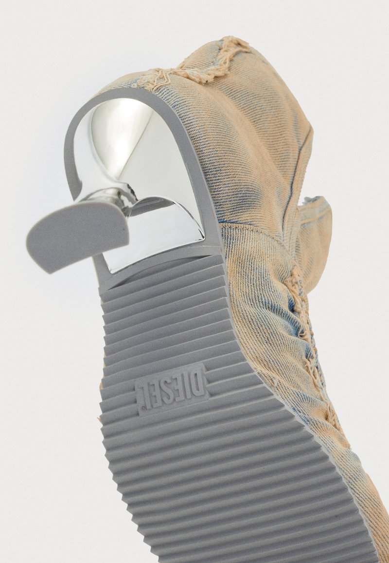 Denim-Pumps mit hellblauem und ausgeblichenem Textur, ausgestattet mit einem chromfarbenen Akzent und einer grauen gerippten Gummisohle. Logo in die Sohle geprägt.
