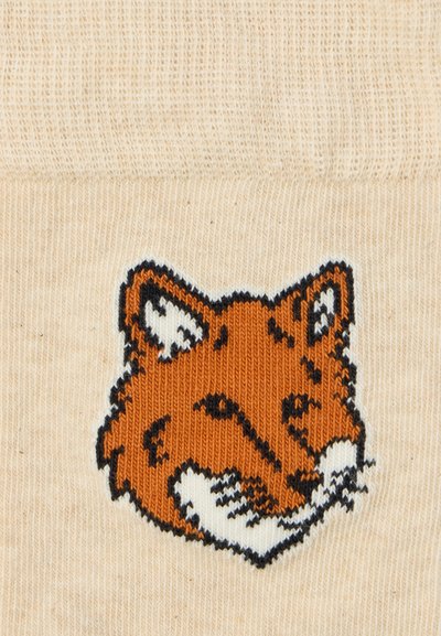 Beige gestrickte Socken mit einem orangefarbenen und schwarzen gestickten Fuchs-Kopf-Design, das detaillierte Gesichtszüge und eine glatte Textur aufweist.