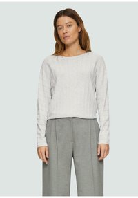 Hellgrau langärmliges Top mit strukturiertem, geripptem Design. Kombiniert mit hoch taillierten, weit geschnittenen grauen Hosen. Minimalistischer, moderner Stil.