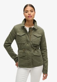 Veste en toile verte avec col, taille à cordon de serrage et quatre poches avant. Fermeture à glissière et à bouton. Texture lisse.