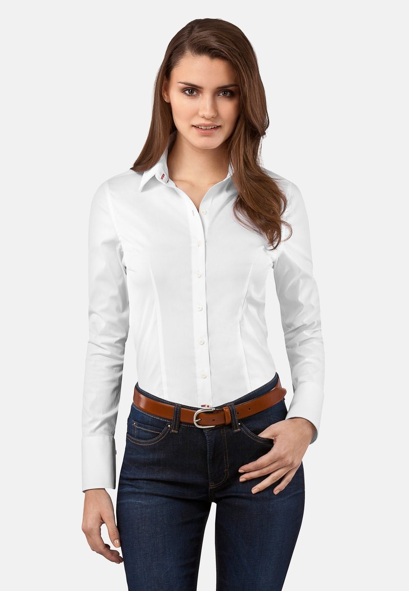 Weißes Hemd mit Knopfleiste, Kragen, langen Ärmeln und schmaler Passform. Kombiniert mit dunklen Jeans aus Denim und einem braunen Gürtel. Einfaches Design, ohne Muster.