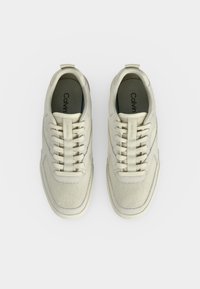 Paire de baskets beiges Calvin Klein avec texture en mesh et cuir, lacées, vues de dessus sur fond blanc uni.