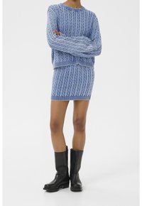 Pull bleu clair en maille avec motif torsadé et jupe assortie. Porté avec des bottines en cuir noir. Texture lisse sur l'ensemble.