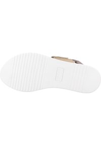 Chaussures avec une semelle en caoutchouc blanc, surface texturée, partie supérieure beige et une sangle réglable pour un ajustement sécurisé.