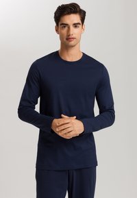 Camisa de manga larga azul marina hecha de una tela suave, con cuello redondo y un corte holgado, sin patrones ni elementos metálicos visibles.