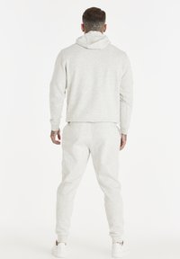 Set in cotone grigio chiaro composto da felpa con cappuccio e pantaloni jogger, caratterizzato da una vestibilità comoda, polsini a coste e cappuccio con cordino. Sneakers completano l'outfit.