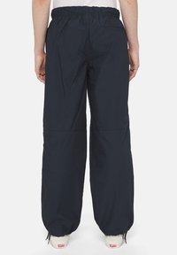 Granatowe, lekkie spodnie nylonowe z elastycznym pasem, zwężanym krojem na mankiecie oraz minimalnym wykończeniem z tyłu.