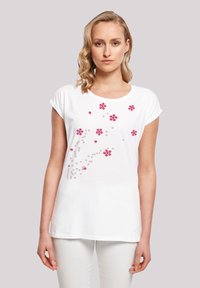 White cotton t-shirt with rolled sleeves featuring pink floral and dot pattern, crew neckline, and relaxed fit.