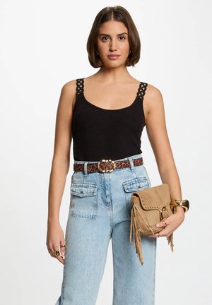 Black tank top with decorative straps, high-waisted light blue denim jeans with pockets, leopard print belt, and a tan fringe handbag.