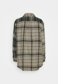 Chemise boutonnée en mélange de coton, arborant un motif écossais mixte en beige, vert et noir. Texture douce avec une coupe décontractée et un pli au dos.