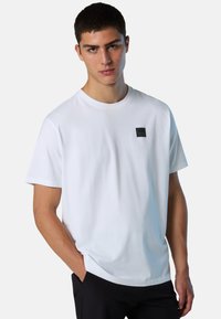 T-shirt bianco in cotone con scollo rotondo, caratterizzato da un piccolo logo nero ricamato sul lato sinistro del petto e una vestibilità comoda. Tessuto morbido, maniche corte.