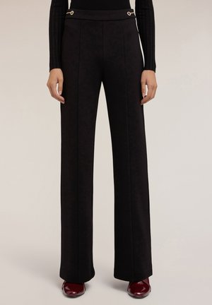 Pantaloni neri a gamba larga in tessuto testurizzato con dettagli in metallo dorato sulla vita. Vestibilità sartoriale con dettagli della cucitura frontale.
