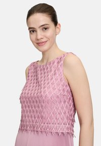 Różowy bezrękawnik z misternym wzorem haftu teksturowego. Wzór zawiera graduowane motywy trójkątne oraz gładką dolną część.
