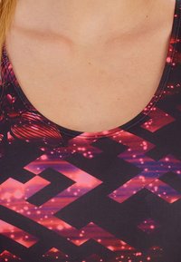 Débardeur ajusté sans manches avec un col rond, base noire et motifs géométriques rose vif et violet avec une finition brillante.